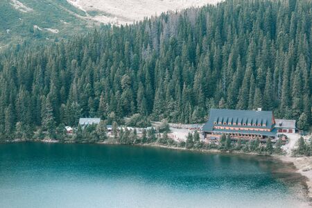 Large wooden hotel on the lake in the pine and mountains