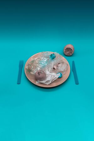Plastic and organic garbage on the plate, concept of bad, harmful and unhealthy foodの写真素材