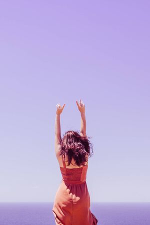 Young girl dancing on a background of surreal purple sea and skyの写真素材
