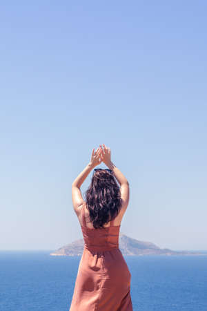 Young girl dancing on a background of blue sea and skyの写真素材