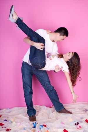 lover, he is carry her on his embrace on pink backgroundの写真素材