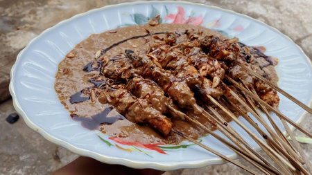 Grilled chicken satay with peanut sauce and crispy fried onion toppings is a popular Indonesian dish loved by many. Skewered and grilled chicken is marinated with a blend of spices, then served with a side of rich and creamy peanut sauce.の写真素材