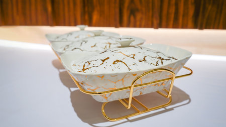This white ceramic vegetable bowl comes with a stunning gold-colored rack that adds a touch of elegance to your table setting.の写真素材