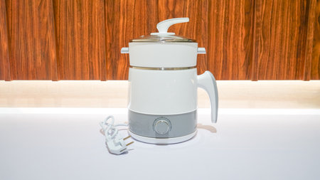 A white electric steamer is a kitchen appliance used for steaming food. It has multiple layers or compartments where food can be placed and cooked simultaneously using steam.の写真素材