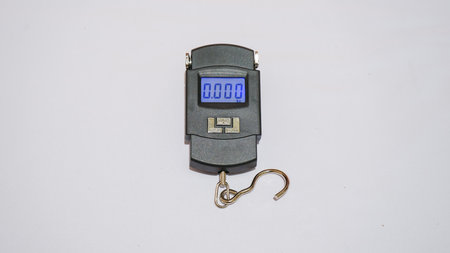 A black digital hanging scale is a portable and convenient device used for weighing various objects that can be hung from its hook.の写真素材