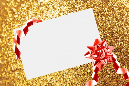 Christmas sheet of paper with bow and ribbons on yellow defocused backgroundの写真素材