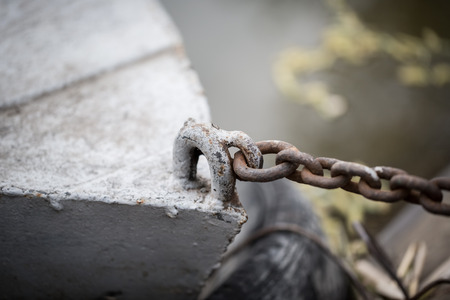 Chained wooden boat is waiting for sunday passengers. Focus is on the hook and the boat in...