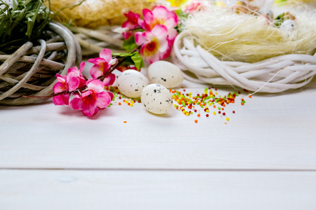 Beautiful Easter background with flowers and nest with eggs on the white painted boards.