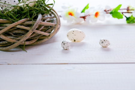 Beautiful Easter background with flowers and nest with eggs on the white painted boards.