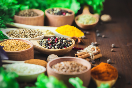 Beautiful colorful spices in wooden spoons and bowls with lettuce, dill and Basil on an old wooden brown table. Free space for your textの写真素材
