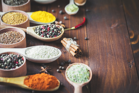Beautiful colorful spices in wooden spoons on an old wooden brown table. Free space for your textの写真素材