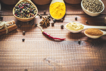 Beautiful colorful spices in wooden spoons on an old wooden brown table. Free space for your textの写真素材