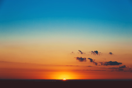 Beautiful blazing sunset landscape at over the meadow and orange sky above it. Amazing summer sunrise as a background.の写真素材