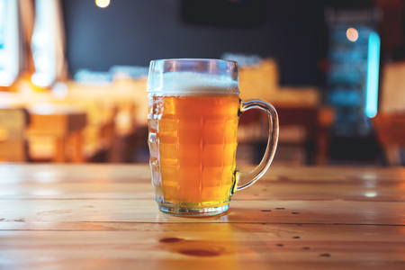 Beautiful background of the Oktoberfest. Glass of cold fresh lager beer on a wooden bar counter in pub with free space for your textの写真素材