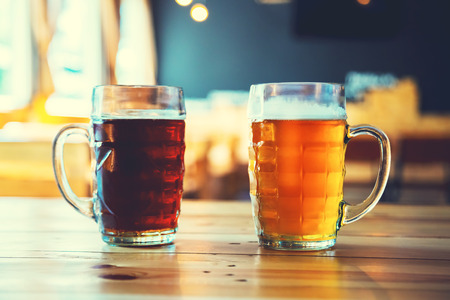 Goblets light and dark beer on a wooden table on a pub background. Assorted alcohol in a Flight Ready for Tastingの写真素材