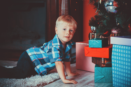 beautiful portrait of a little boy on a background of the gifts in the New year, the room under the Christmas tree. The idea for postcards. Soft focus. Shallow dofの写真素材