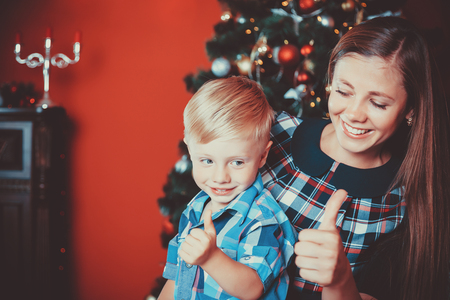 beautiful portrait of happy mother and son on the background of the Christmas tree in new year room. The idea for postcards. Soft focus. Shallow dofの写真素材