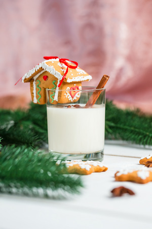 Christmas Gingerbread House with glass milk and festive branches fir. Homemade delicious gingerbread cookies on the wooden background.の写真素材