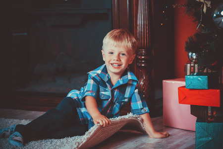 beautiful portrait of a little boy on a background of the gifts in the New year, the room under the Christmas tree. The idea for postcards. Soft focus. Shallow dofの写真素材