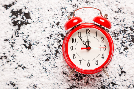 Christmas red clock and snow. Beautiful New Year background with free space. The concept of time