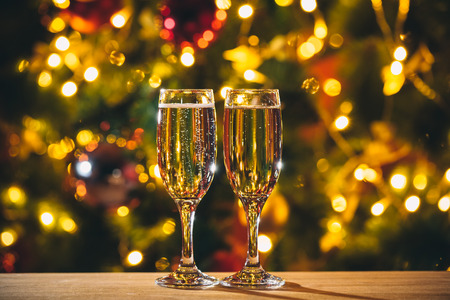 Beautiful two glasses of champagne standing on the table in the background of a blurred room with a decorated Christmas tree and fireplace. Soft focus. Shallow DOFの写真素材