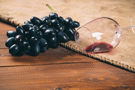 glass of red wine and grape on wooden background with burlapの写真素材