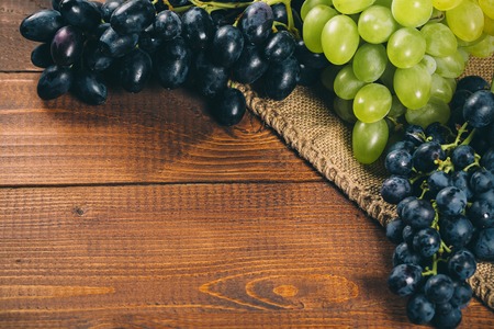 Bunch of white and blue grapes with burlap on wooden backgroundの写真素材