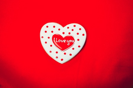 Heart-shaped biscuits on red pillow, for Valentine's Day. Gingerbread Valentine on wooden background. Free space for your textの写真素材