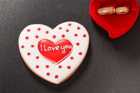 Beautiful gingerbread heart and wedding rings on a black background. Postcard for Valentine day or Wedding. Free space for textの写真素材