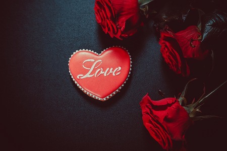 Beautiful gingerbread heart and red roses on a black background. Postcard for Valentine's day, March 8, mother's day or Wedding.の写真素材