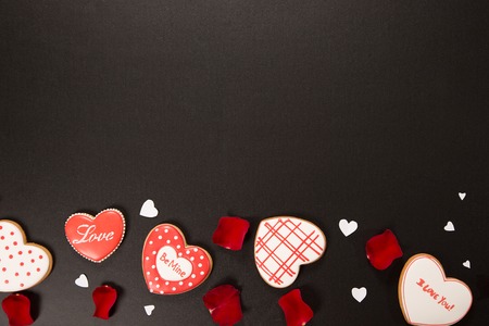 Beautiful gingerbread heart and red petals roses on a black background. Postcard for Valentine's day, March 8, mother's day or Wedding. Free space for textの写真素材