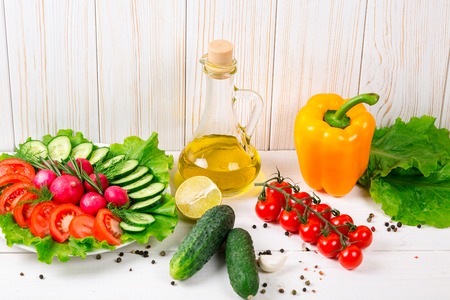 Cucumbers, radish, tomatoes cherry, olive oil, herb and spices on old white wooden background. Set for healthy foods. Ingredients for saladの写真素材