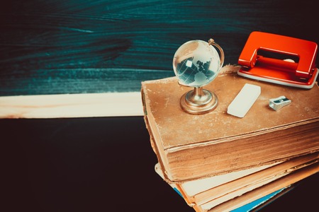 Old blackboard with chalk, books, a globe and a pencil. A beautiful backdrop for education, a free space for your textの写真素材