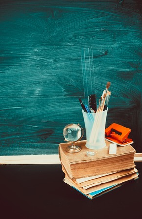 Old blackboard with chalk, books, a globe and a pencil. A beautiful backdrop for education, a free space for your textの写真素材