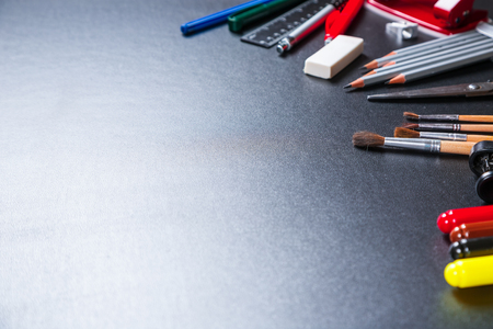 Old blackboard with chalk, stapler, scissors, pencils and stationery.の写真素材