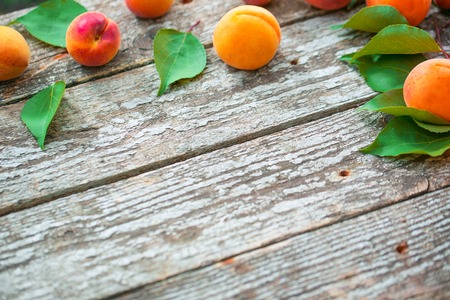 Beautiful ripe orange apricots with leaves on old wooden boardsの写真素材