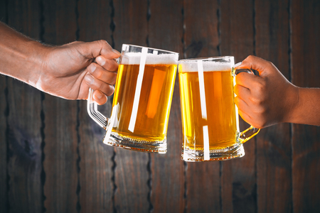 Two friends toasting with glasses of light beer on the wooden background. Beautiful background of the Oktoberfestの写真素材