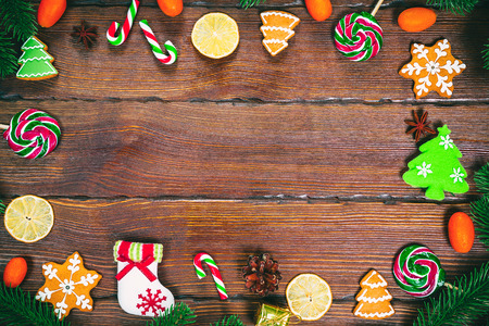 Christmas gingerbread cookies homemade on wooden table with candies, Christmas tree branches and New Year decorations. Xmas frame backgroundの写真素材