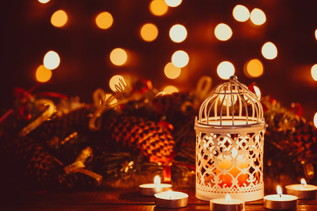Christmas lantern with burning candles and garland on vintage wooden table with golden bokeh. Free spaceの写真素材