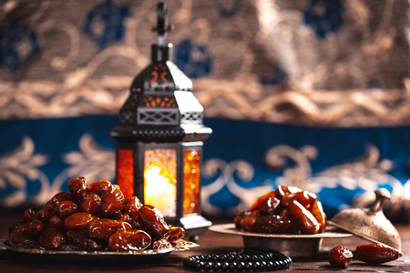 The Muslim feast of the holy month of Ramadan Kareem. Beautiful background with a shining lantern Fanus and dried dates on wooden boards. Free space for your textの写真素材
