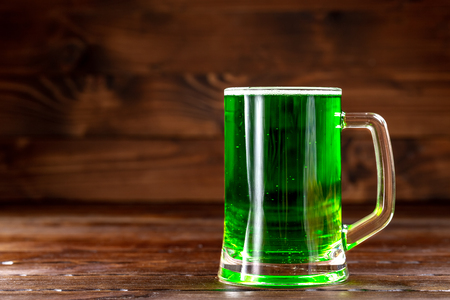 Glass mug with green beer on a rustic wooden surface. Festive background for St. Patrick's day. Free spaceの写真素材