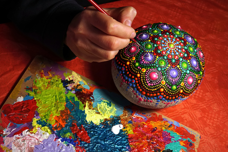 Drawing with a brush a dot mandala on a stoneの写真素材