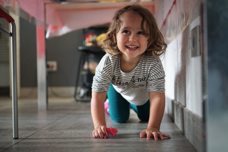 little girl playing under the table and smilingの写真素材