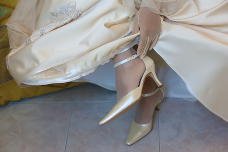 the bride touches the strap of shoes closeupの写真素材