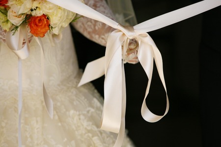 the bride unties the bow before leaving the house closeupの写真素材