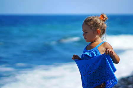 Little girl in a blue dress playing on the Paradisos beach in Santorini, Greeceの写真素材