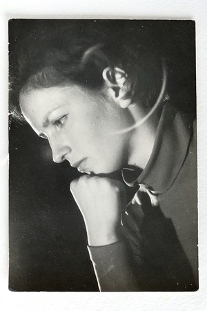 Old black and white photo of young woman in profile, looking down