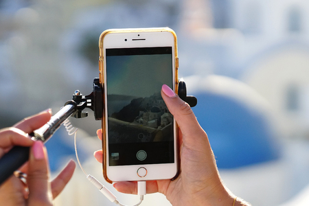 OIA, GREECE, September 19, 2018 An Asian tourist takes a photograph using a cell phoneのeditorial素材