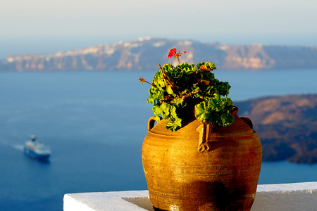 Beautiful ancient amphora with red geranium and view of the caldera in Santoriniの写真素材