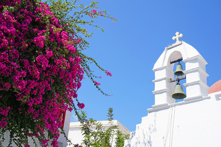 Beautiful view of a bell tower with old bells and pink bouganvillea in Mykonos, Greeceの写真素材